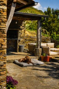 Rustic outdoor terrace with stone barbecue, lounge seating and mountain views at Peregrinus Rio de Frades in Arouca.
